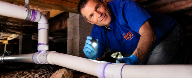 Bear Hug Plumbing technician working in crawlspace