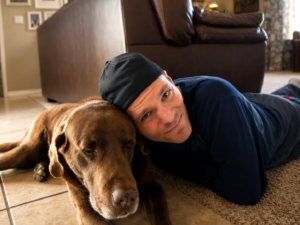 Marty with Bear the chocolate Labrador resting together in their Flagstaff Arizona home.
