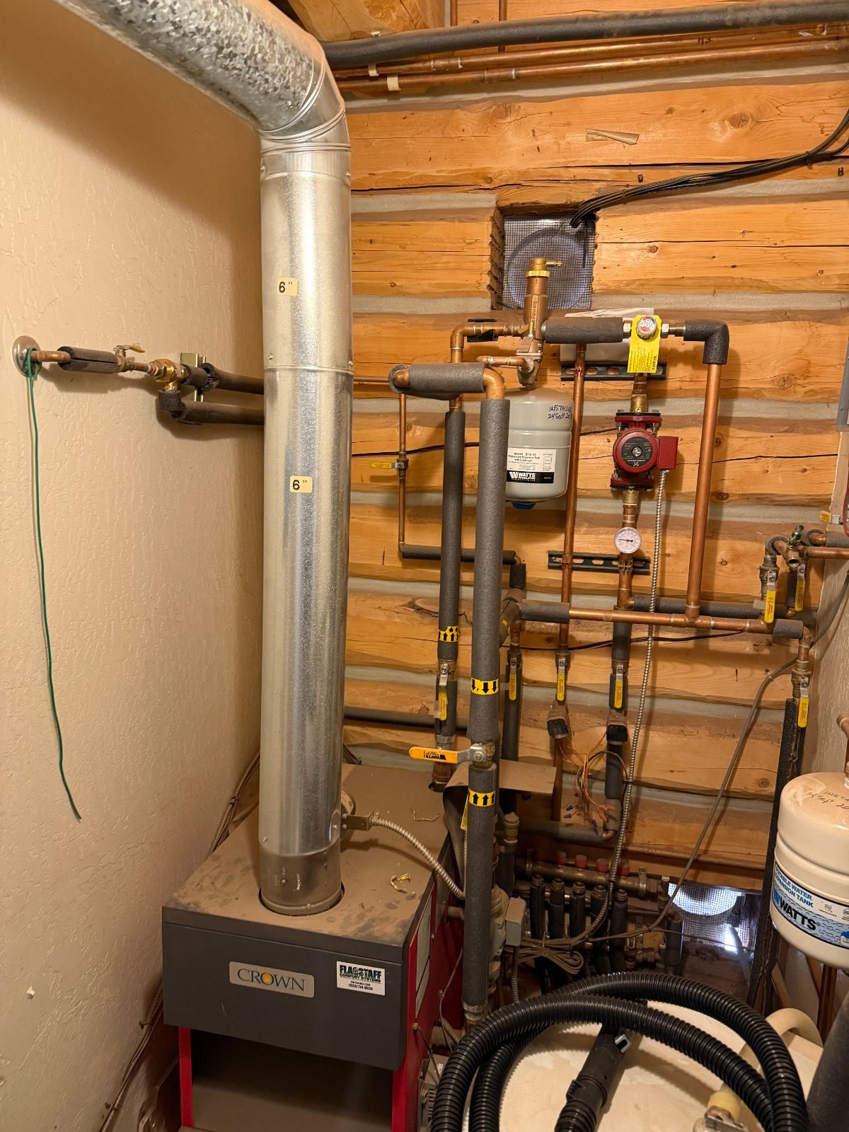 Boiler, circulator pumps, and radiant floor heating piping in the mechanical room of a log home in Doney Park, Flagstaff, AZ