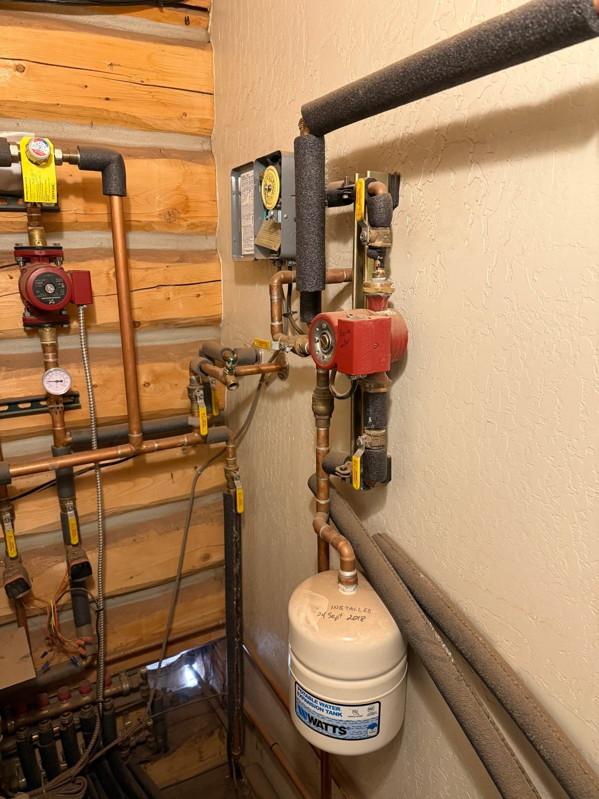 Red circulator pump and expansion tank on a radiant floor heating system in a Flagstaff, AZ log home